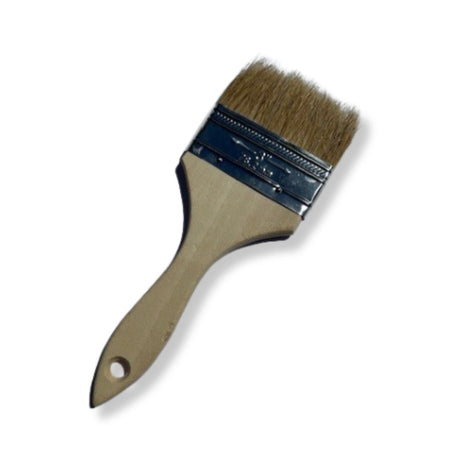 Pinceau plat à manche en bois et poils naturels, posé sur une surface blanche