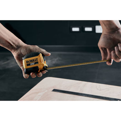 Hands measuring a board with the DeWalt 25 ft tape measure
