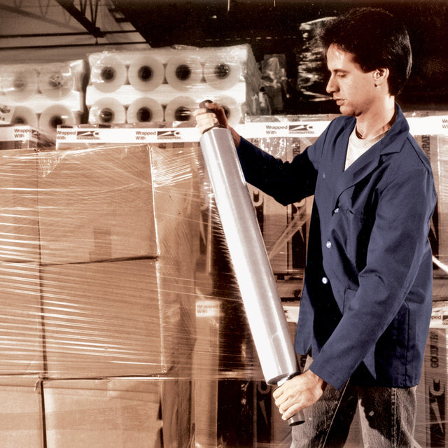 Worker in a blue coat wrapping a pallet of boxes with stretch film