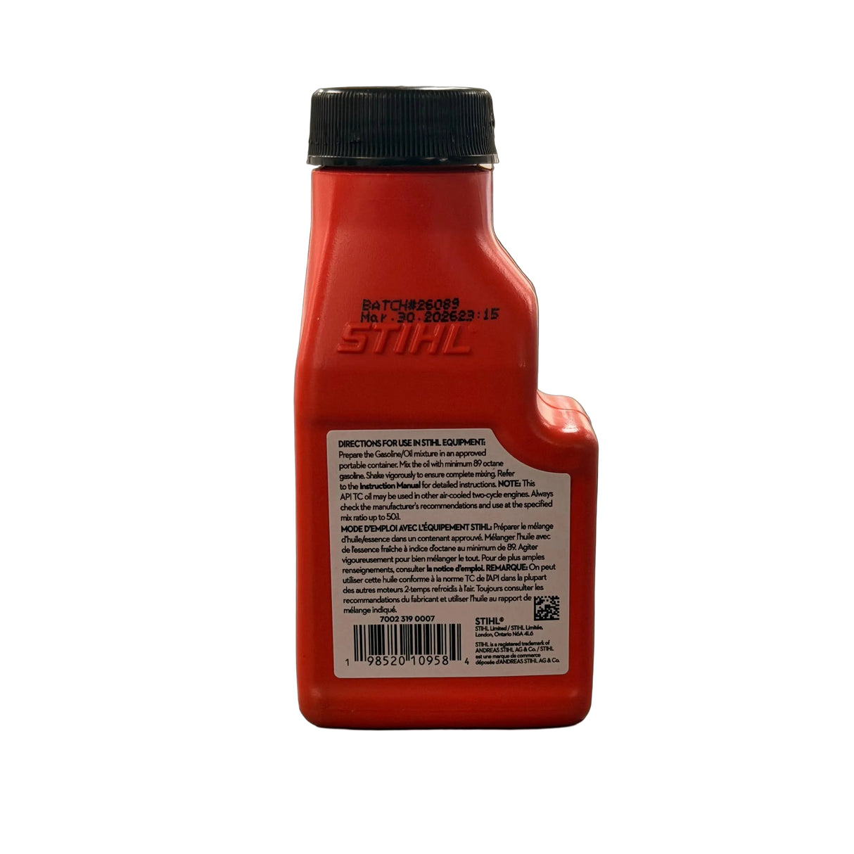 Back of a red STIHL 100 ml oil bottle showing bilingual directions for use and barcode