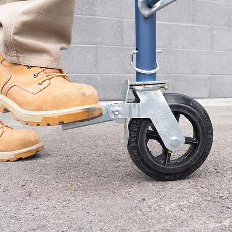 Travailleur actionnant du pied le frein d'une roulette d'échafaudage 8 x 2 po